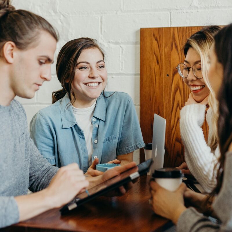 Vier junge Menschen im Gespräch in einem Café – Symbol für offenen Austausch, Vertrauen und psychologische Ressourcen im Umgang mit KI im HR.